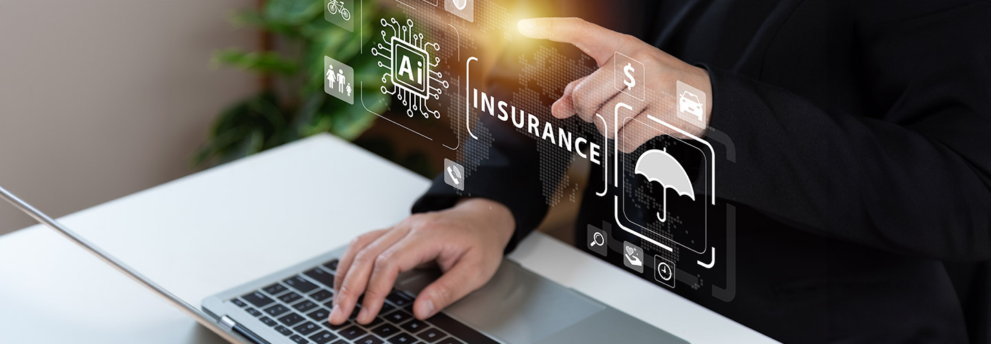 A business person has one hand on a laptop keyboard and one hand pointing to the word "insurance" in front of them.