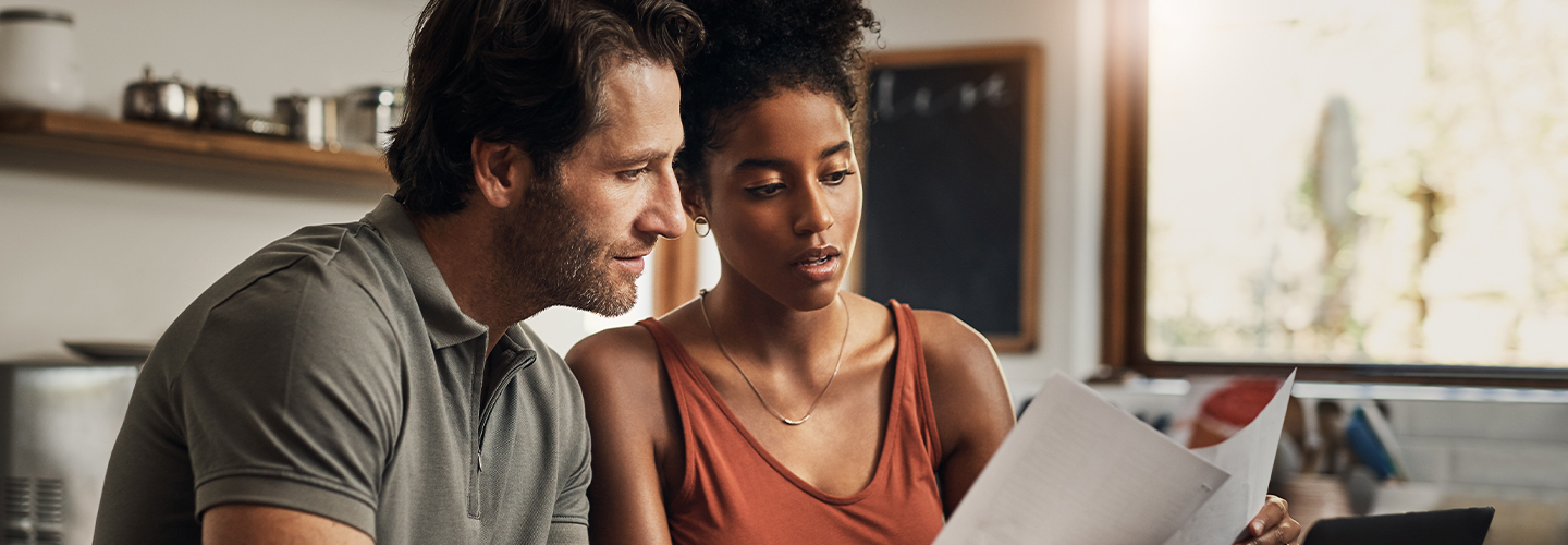 A couple sits at their kitchen table looking at their finances together.