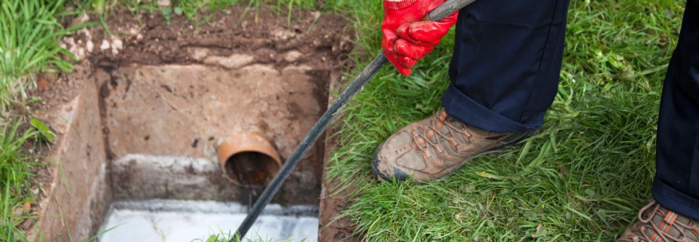 Person working on a sewer system in grass