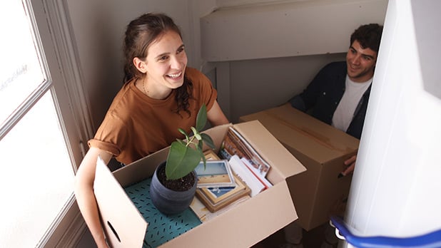 Two people carrying moving boxes up a flight of stairs