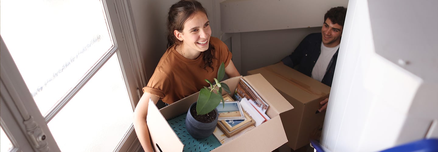 Two people carrying moving boxes up a flight of stairs