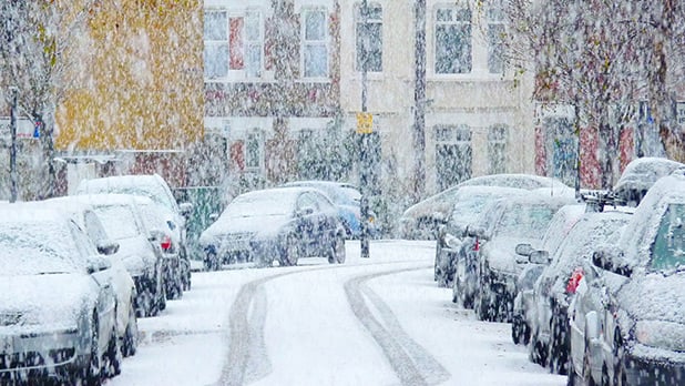 City road with cars covered in snow
