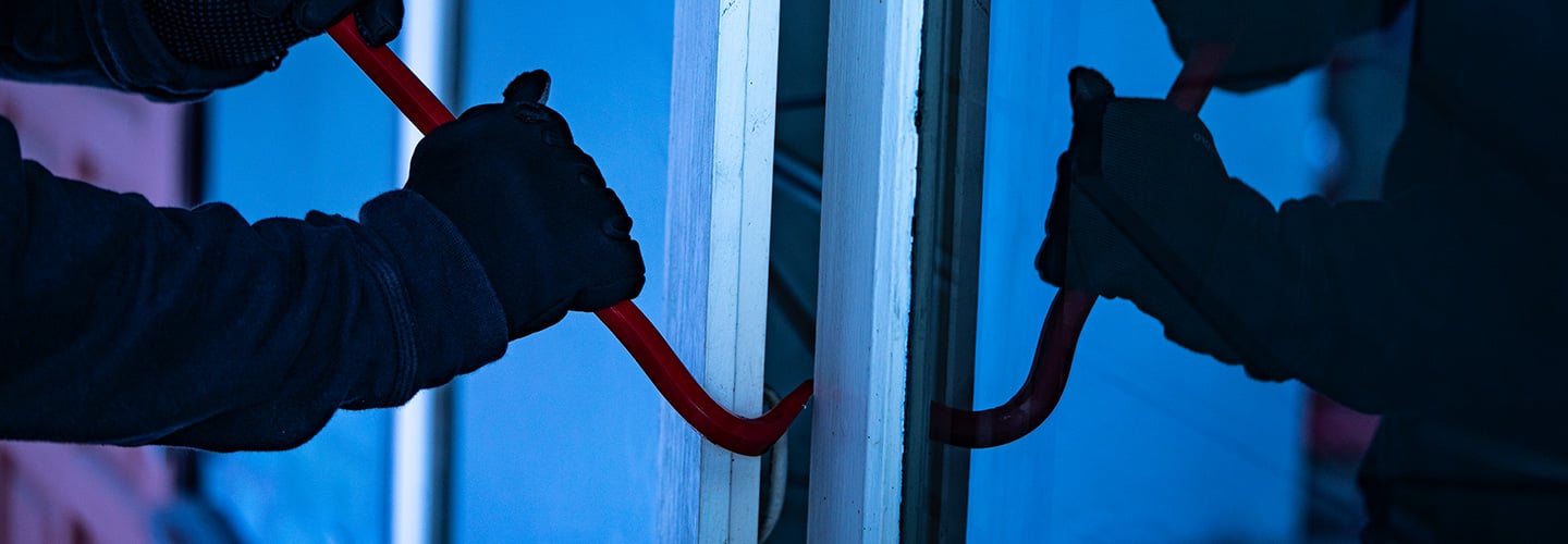 Person using a crowbar in attempts to open a window