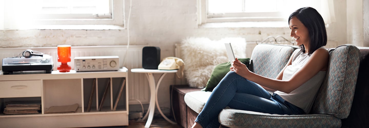 Person sitting on a couch looking at a tablet