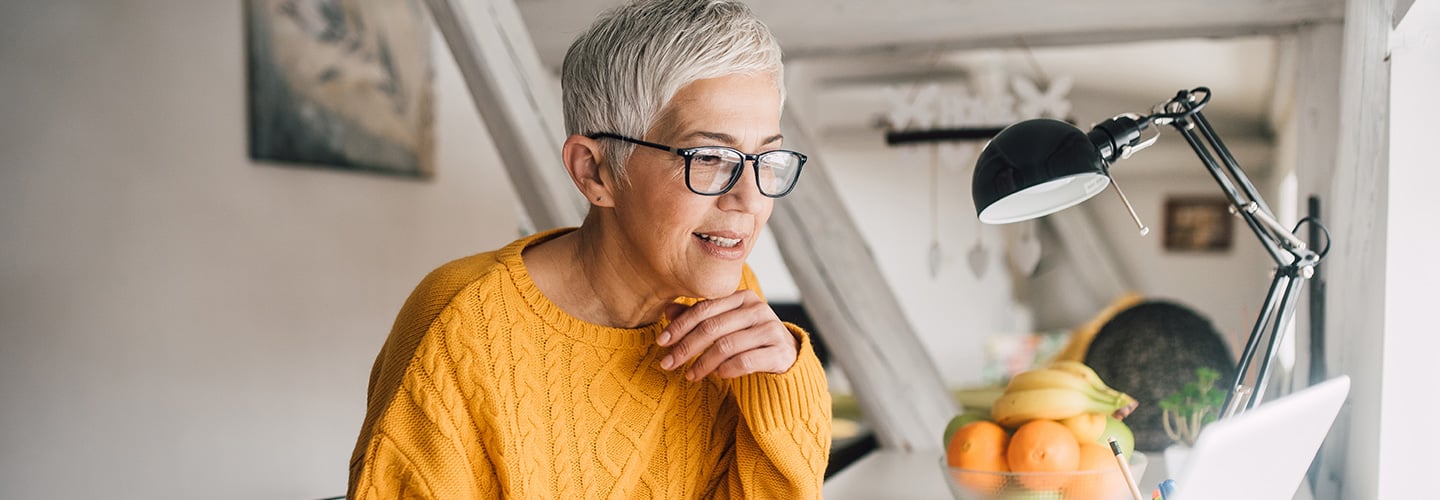 woman holding a pen looking at a laptop