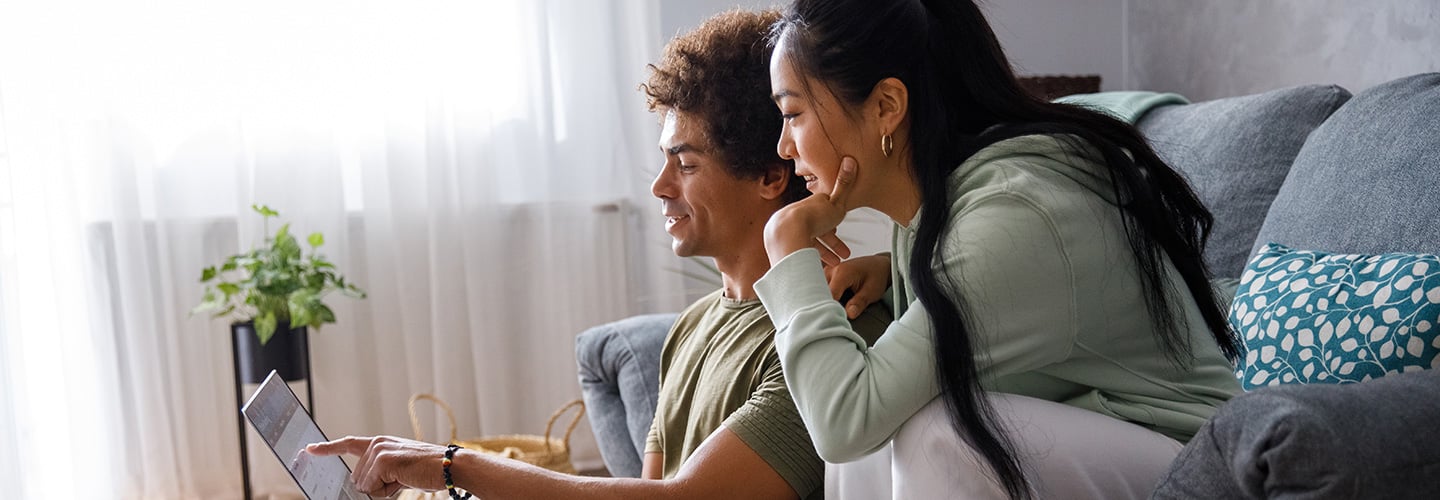 a couple sitting together and looking at a laptop