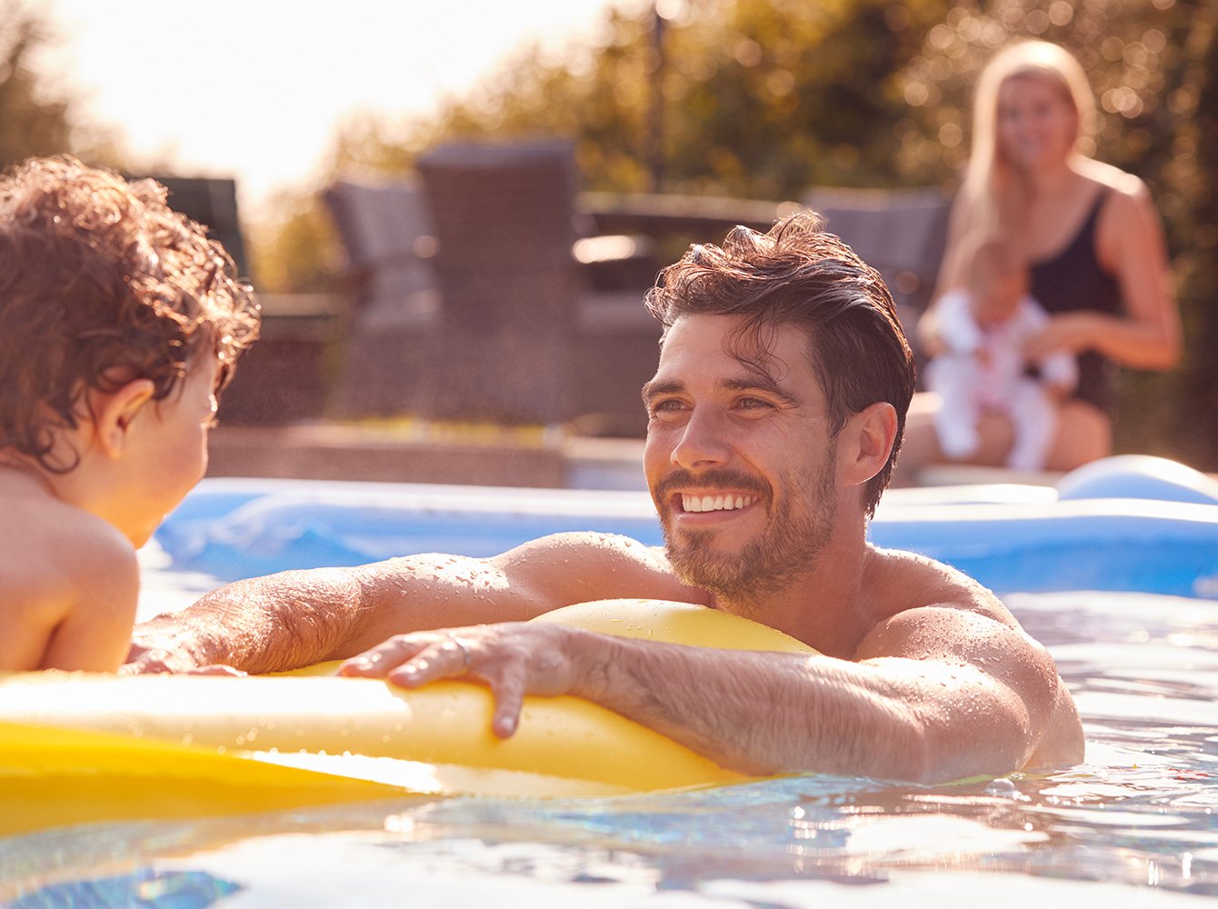 family playing and smiling in the pool on a sunny day