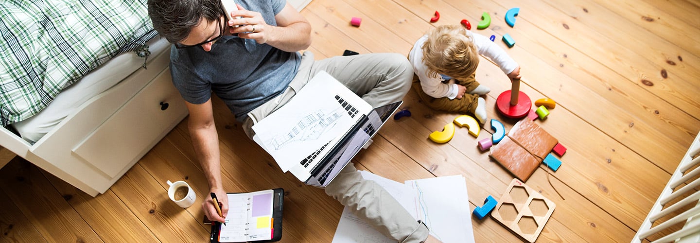 Man sitting on the floor working with a child playing on the floor by him