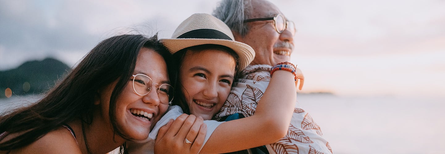 a family of two young women and an older man are smiling and hugging