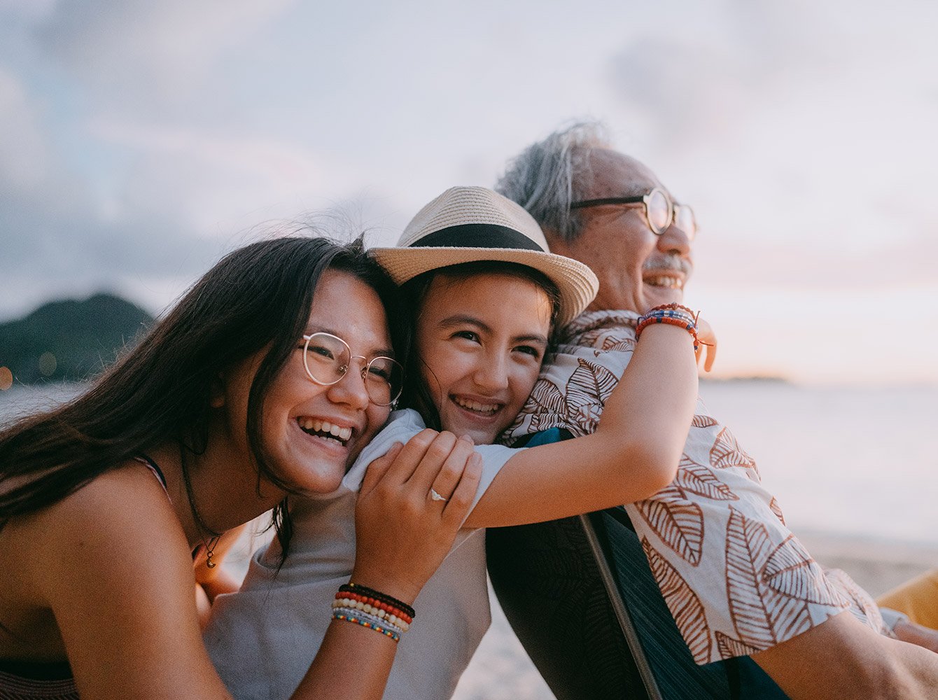 a family of two young women and an older man are smiling and hugging
