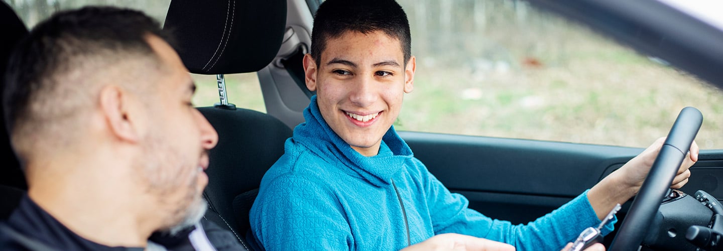 teenager learning to drive with an adult in the passenger seat