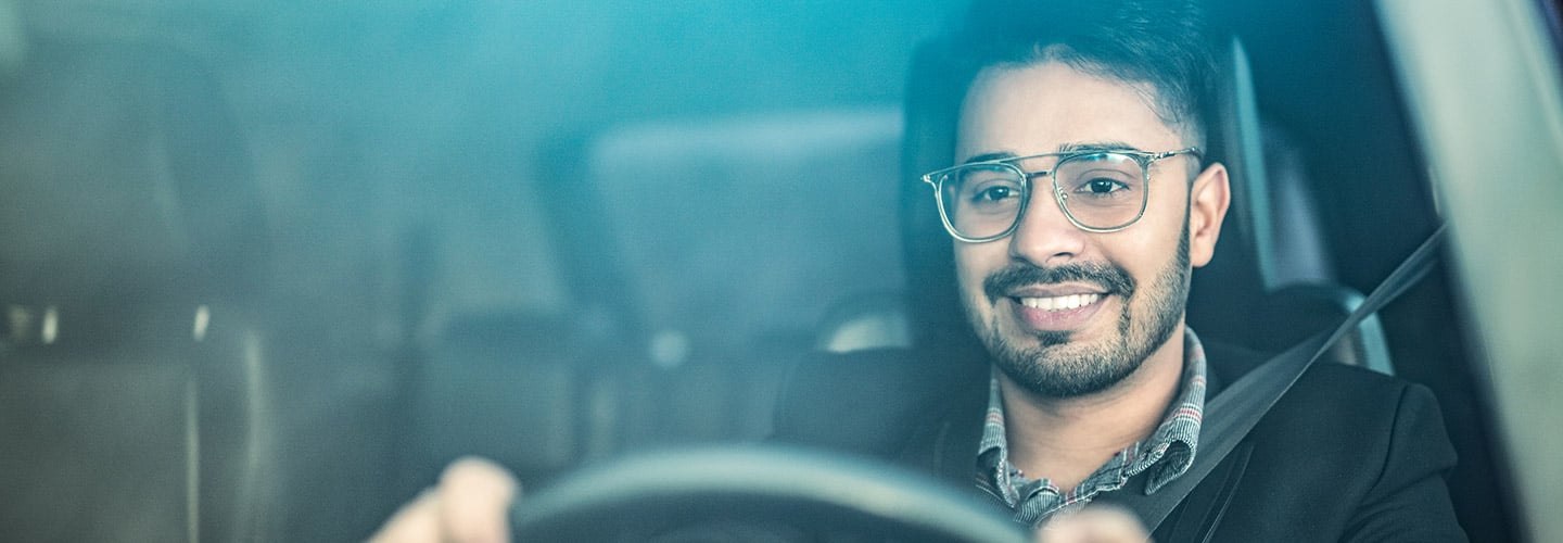 smiling man with his hands on a steering wheel