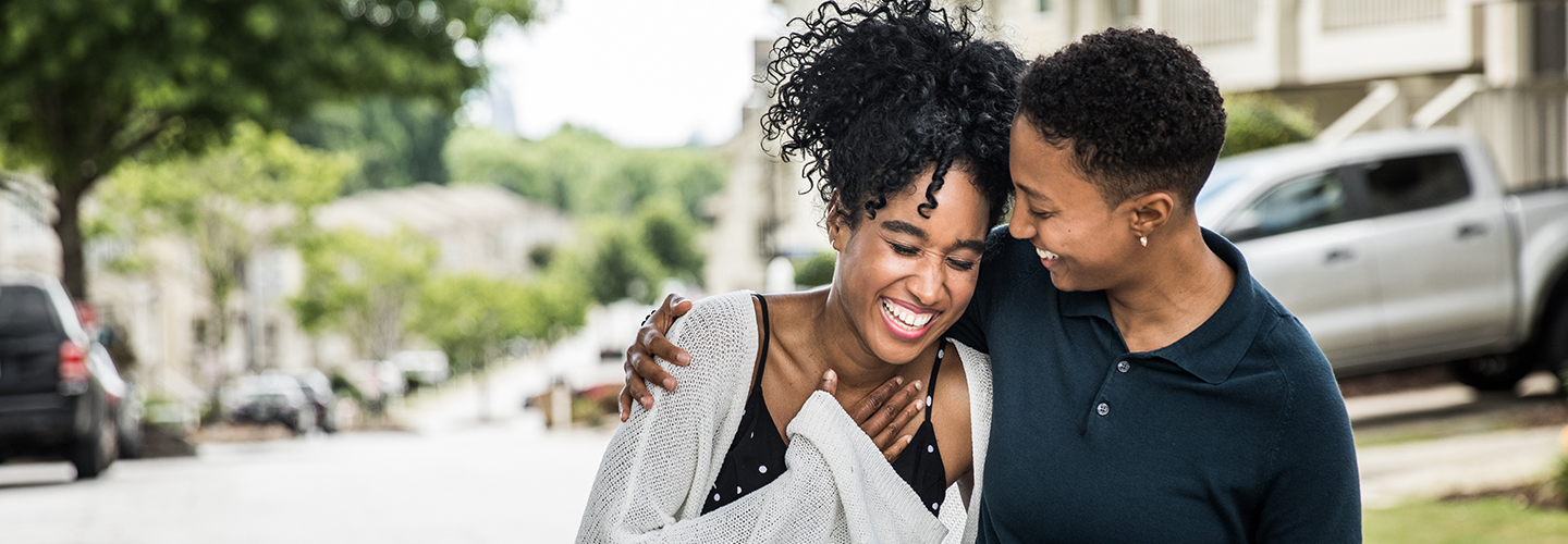 A couple walking down the street while laughing.