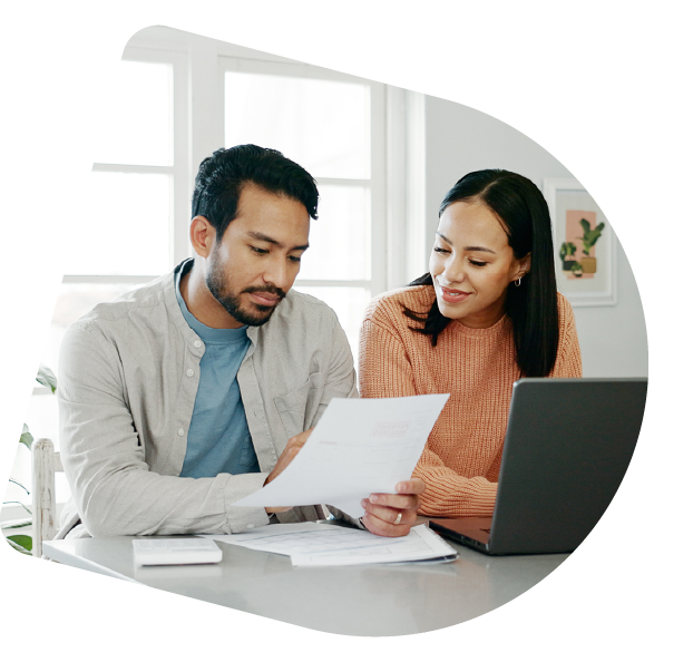 A couple is looking at paperwork together while sitting at the kitchen counter.
