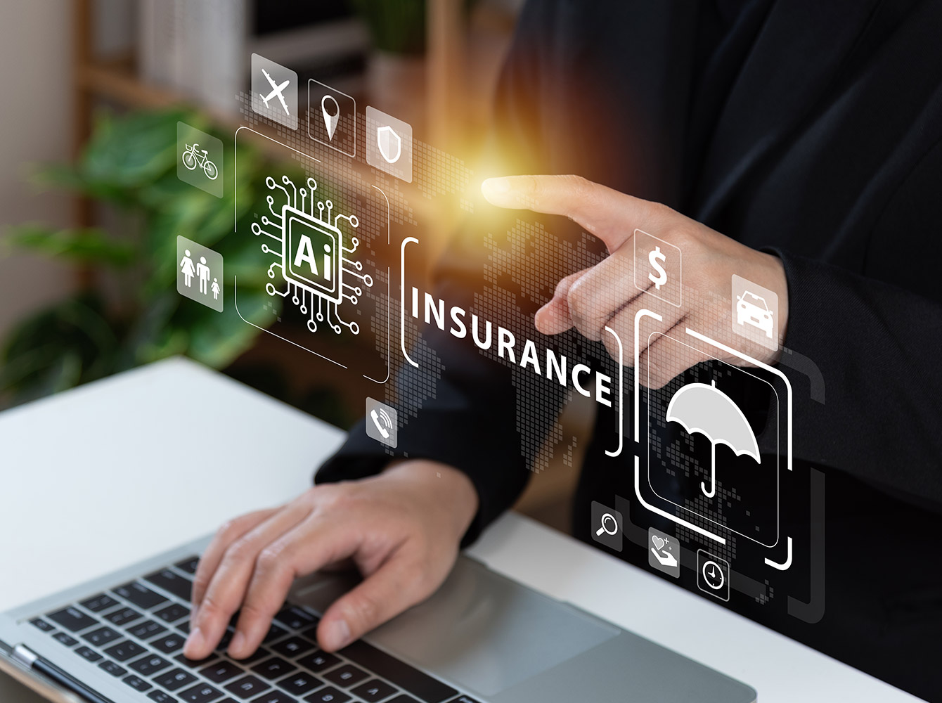 A business person has one hand on a laptop keyboard and one hand pointing to the word "insurance" in front of them.