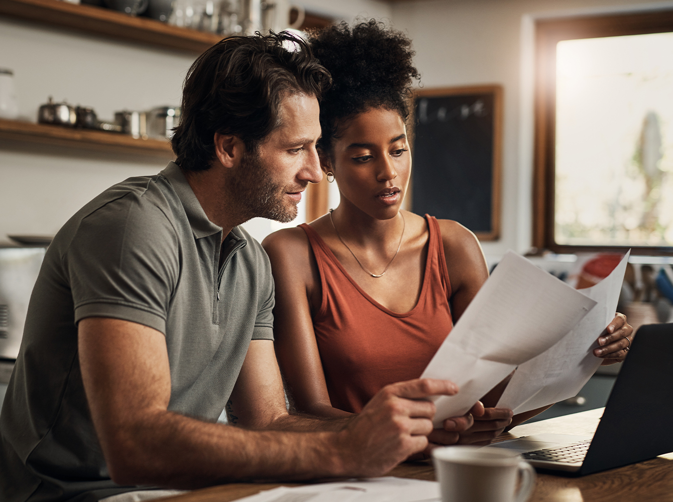 A couple sits at their kitchen table looking at their finances together.