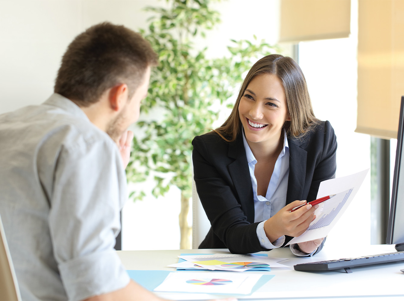 Woman holding a sheet of paper and pointing to it to man