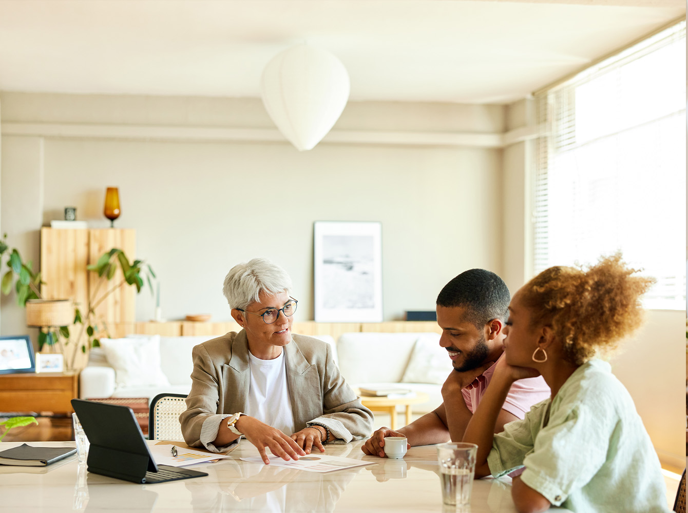 A couple is sitting at a table with someone that is explaining paperwork to them.
