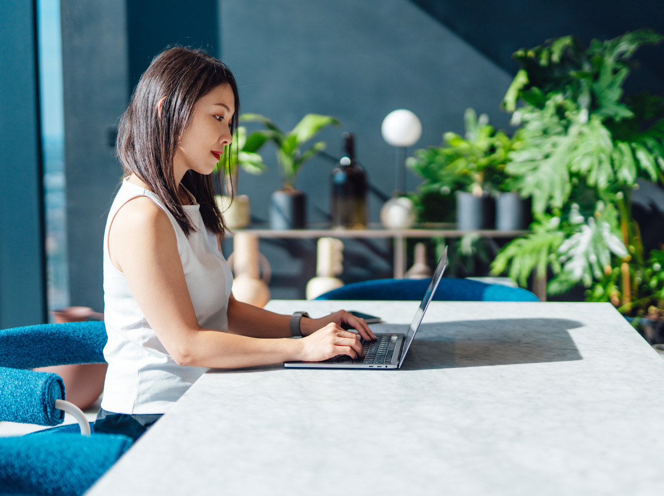 A woman is sitting at a desk and working on a laptop.