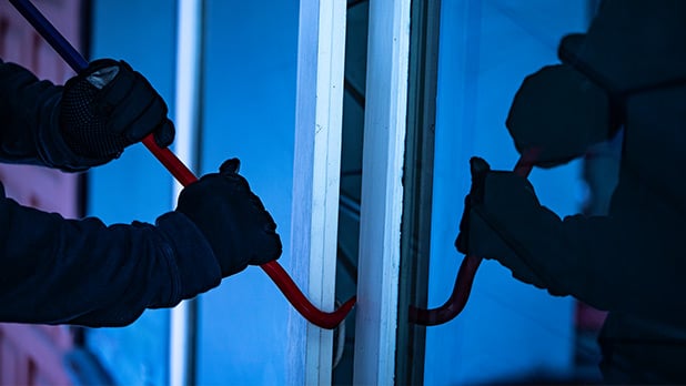 Person using a crowbar in attempts to open a window