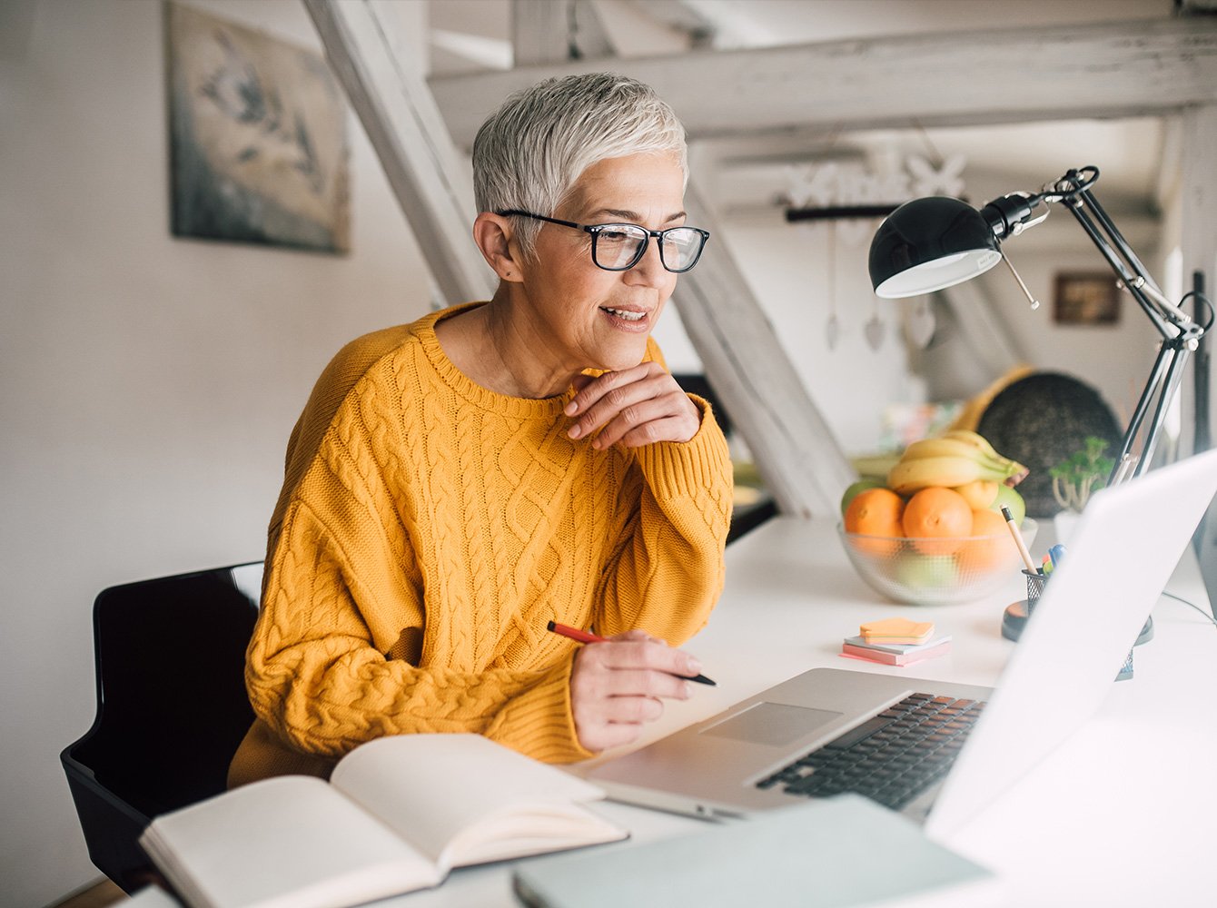 woman holding a pen looking at a laptop