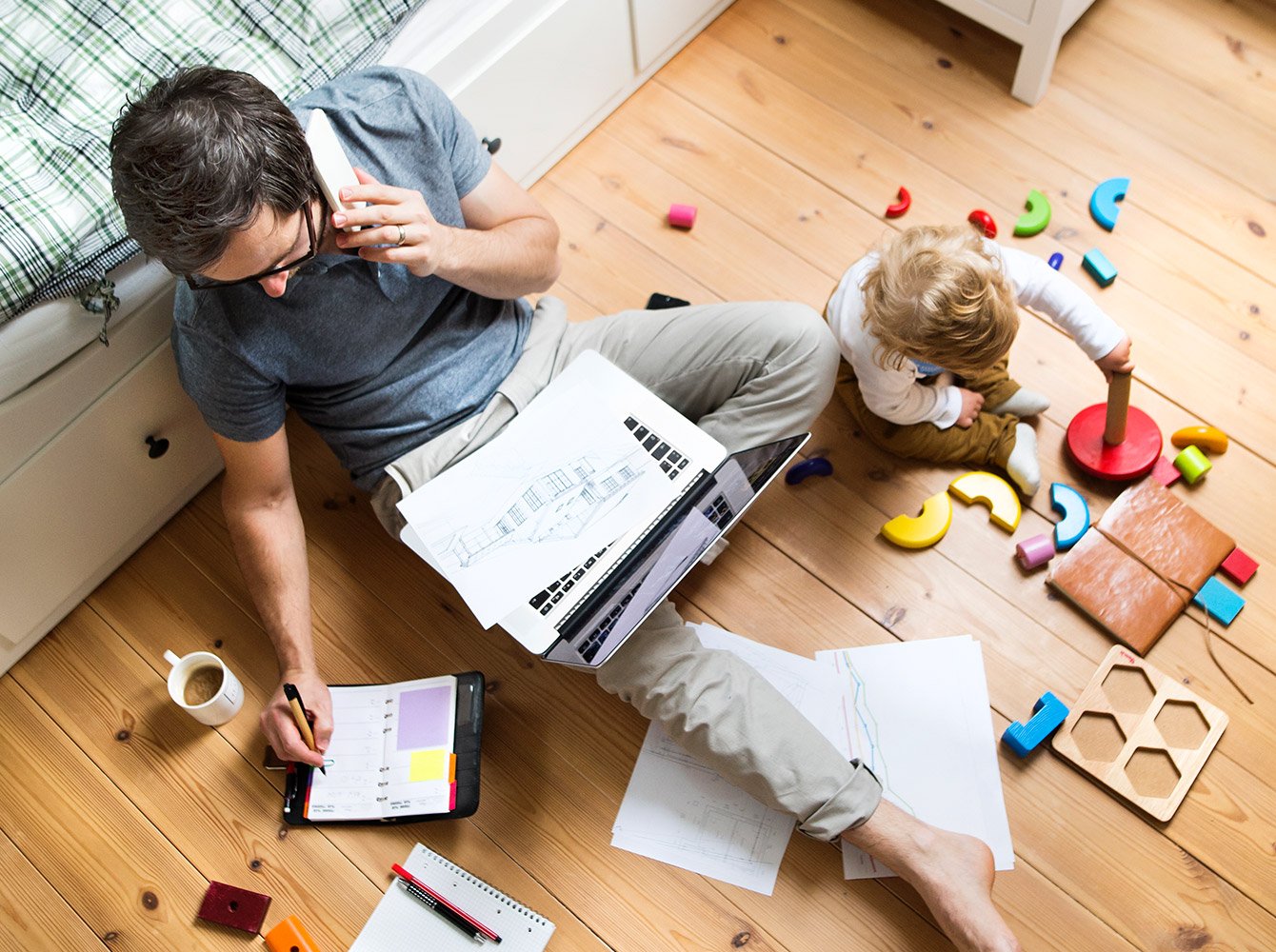 Man sitting on the floor working with a child playing on the floor by him