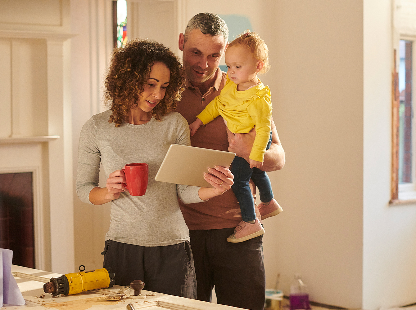 A family is looking at a tablet while standing in a house.