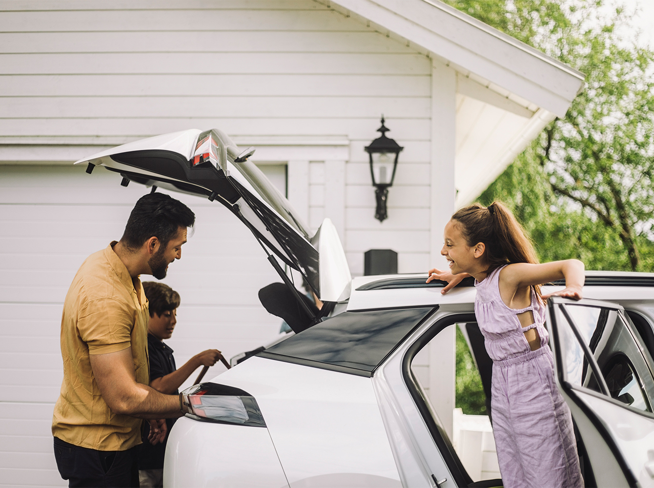 A father and his kids are packing up a vehicle.