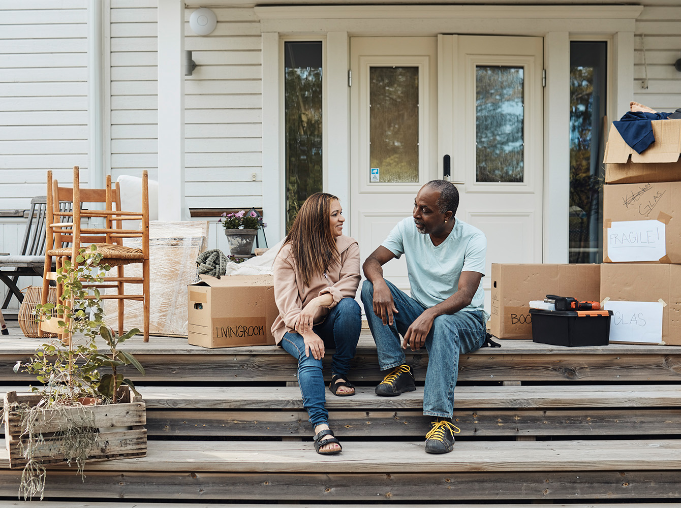A couple is sitting on the front step of a house.