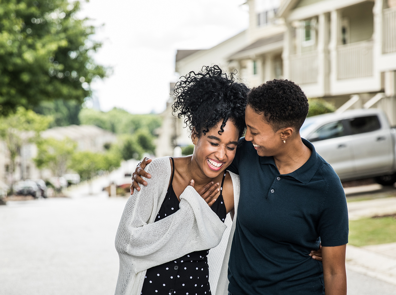 A couple walking down the street while laughing.