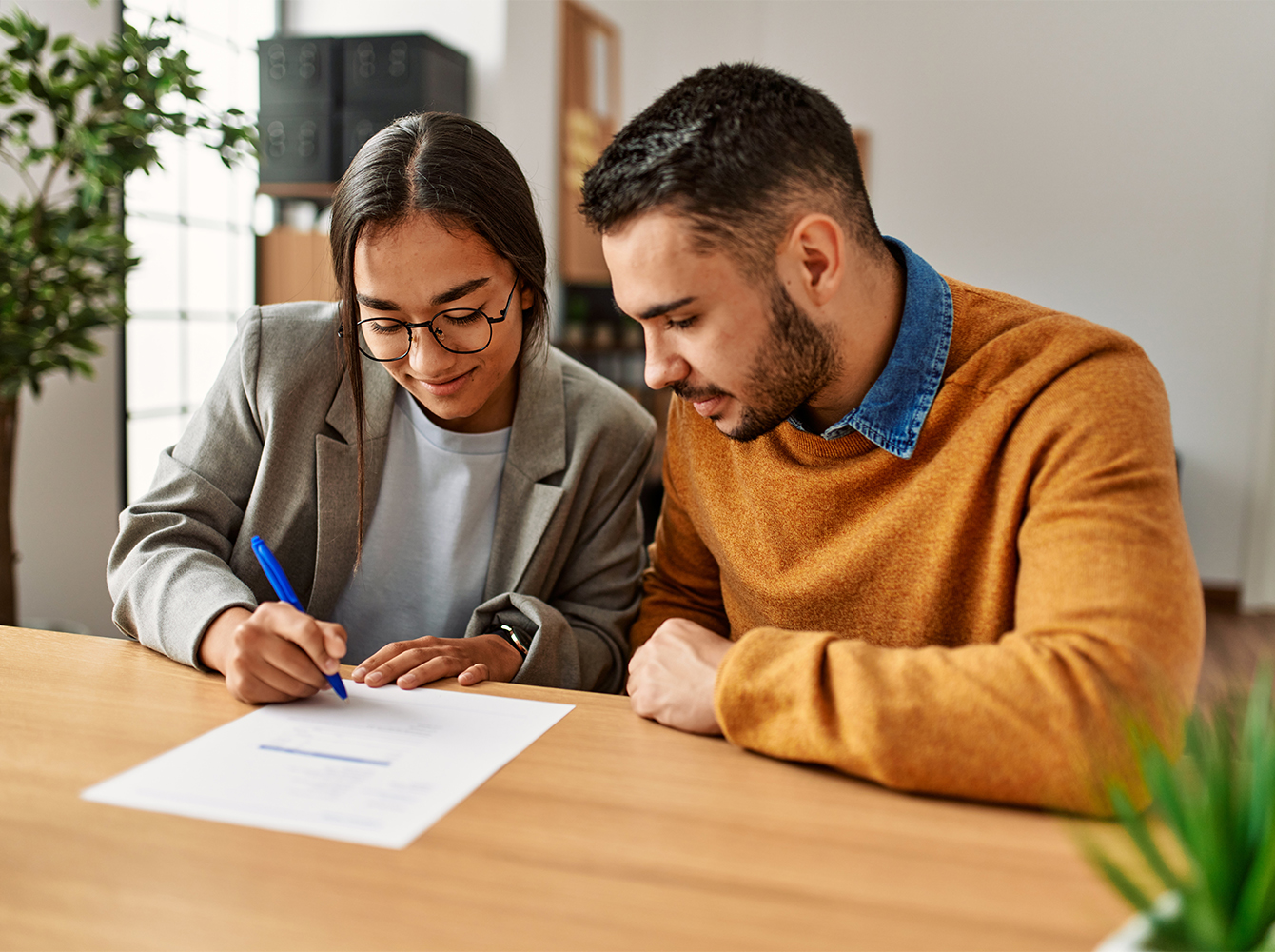 A woman and man are sitting at a table going through paperwork together.