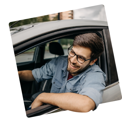A man is leaning out of the window of a car he is driving.