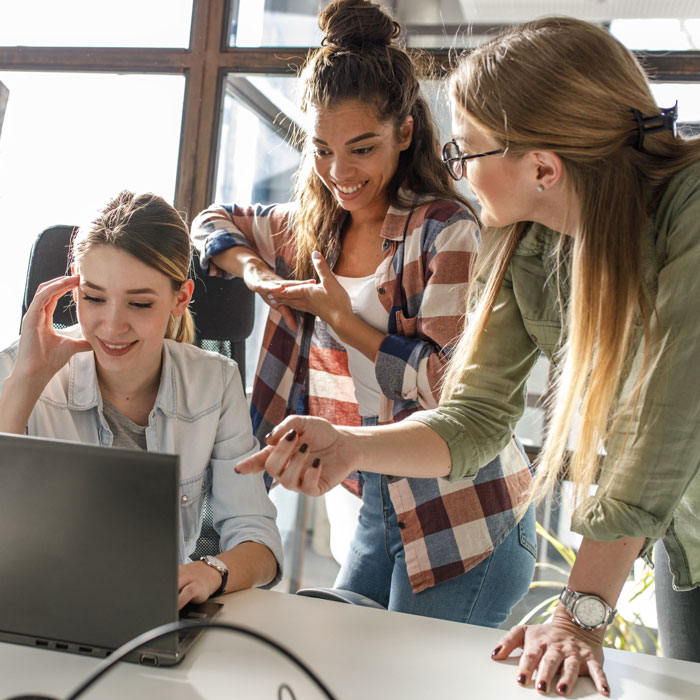 A group of women programming on a computer