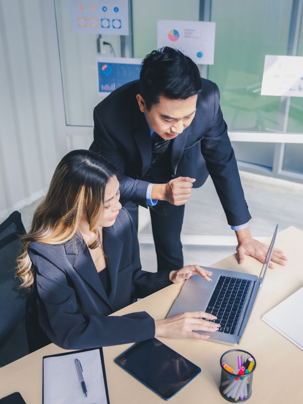 A man and woman working on a laptop in an office 