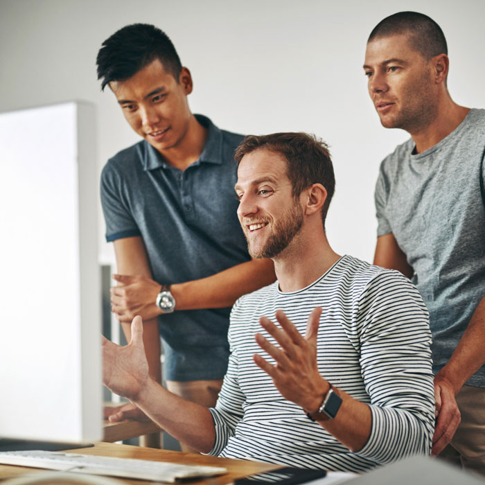 Three happy guys looking at a monitor