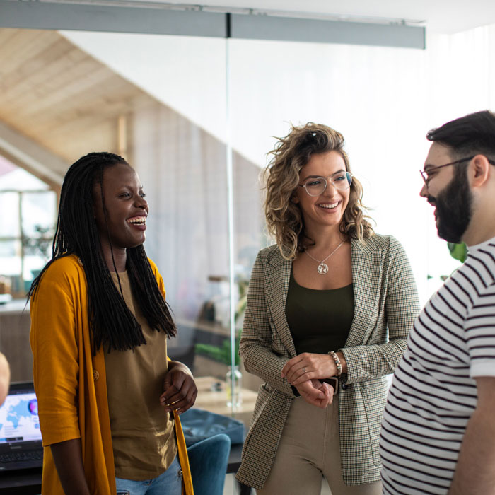 A multiethnic group smiling and talking in an office