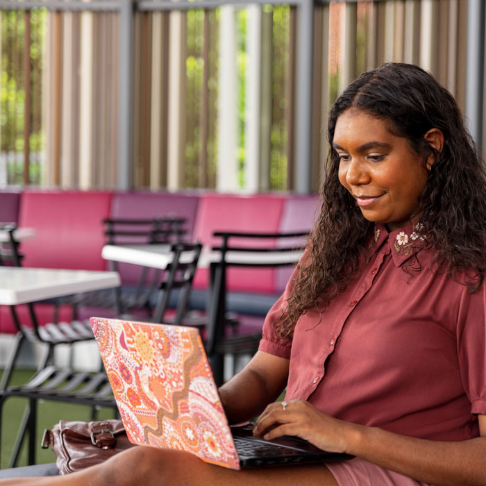 A woman working on a laptop in a cafeteria