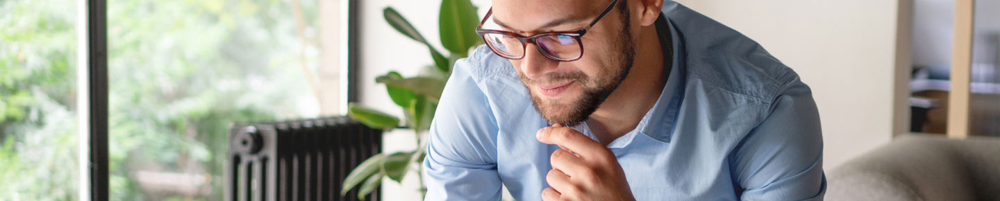 A smiling man looking at a tablet while sitting down