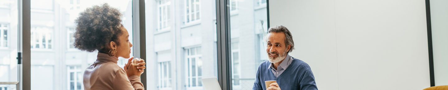 A man and a woman sitting in a conference room and smiling