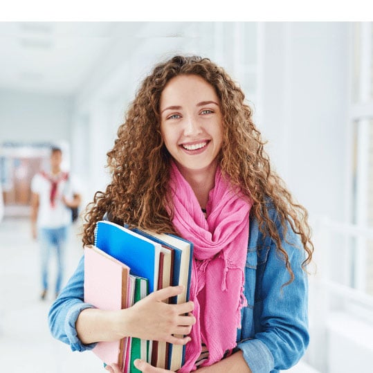 Academic student holding textbooks in a collegiate hallway