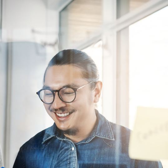 Two men stand in an office looking at a tablet; ISC2 CC cybersecurity certification for career transitioners and entry-level professionals advances to a new format.