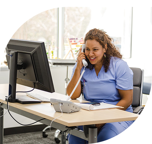Smiling female nurse with computer calling on phone at hospital