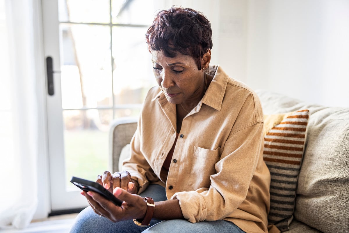Woman sitting on couch looking at phone