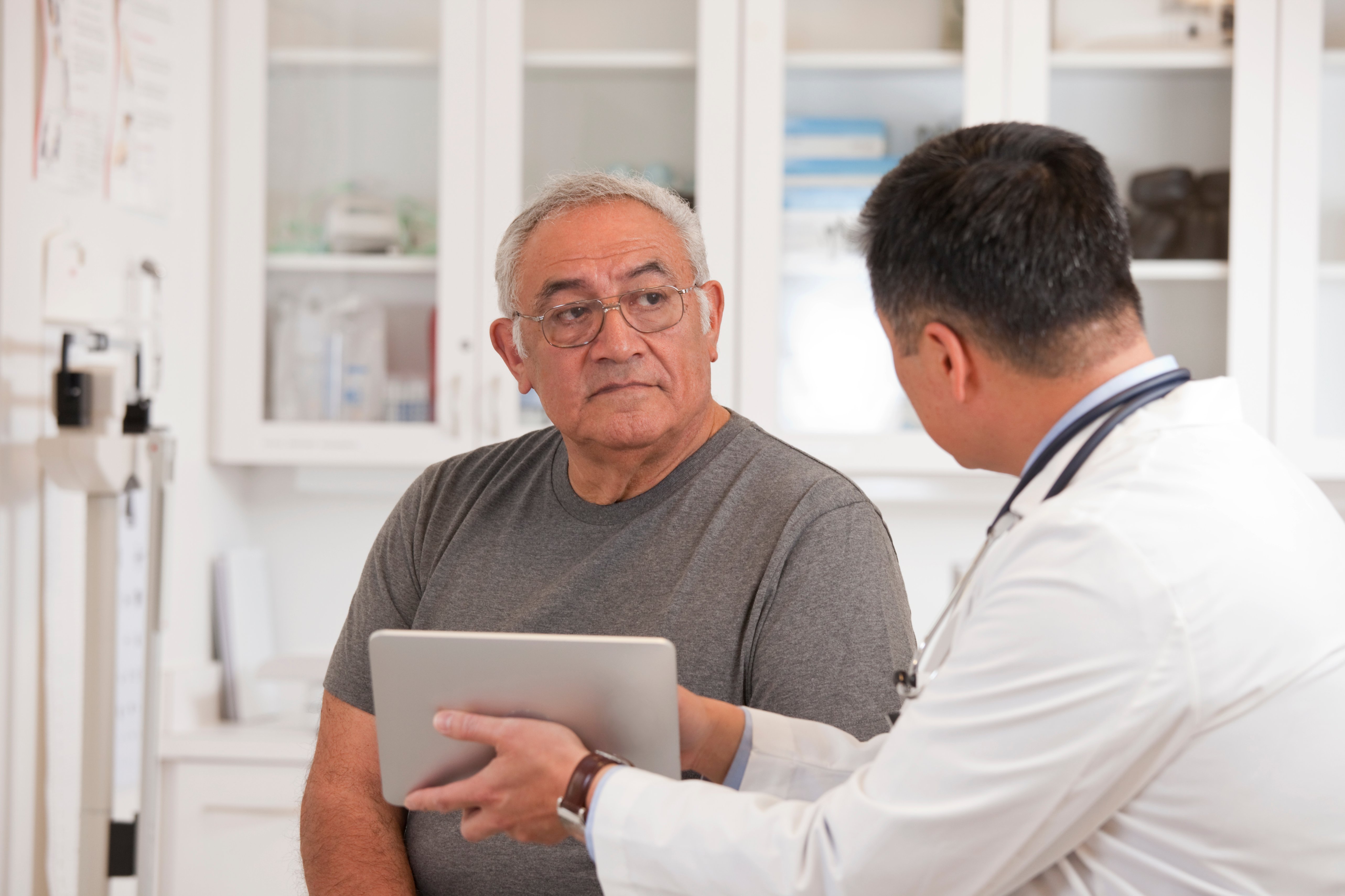 Male doctor showing male patient ipad