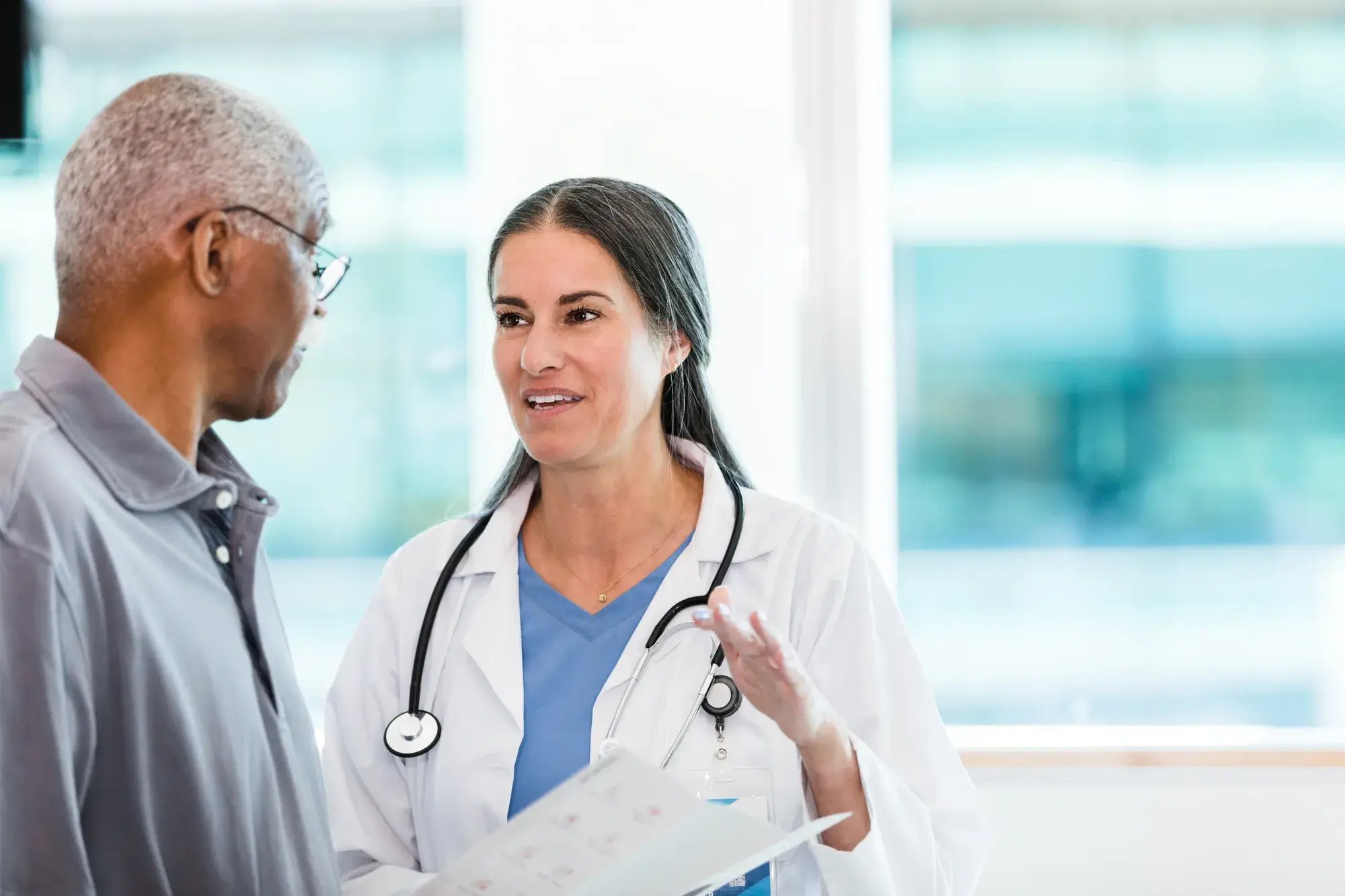 Female doctor and male senior patient discuss rehabilitation options.