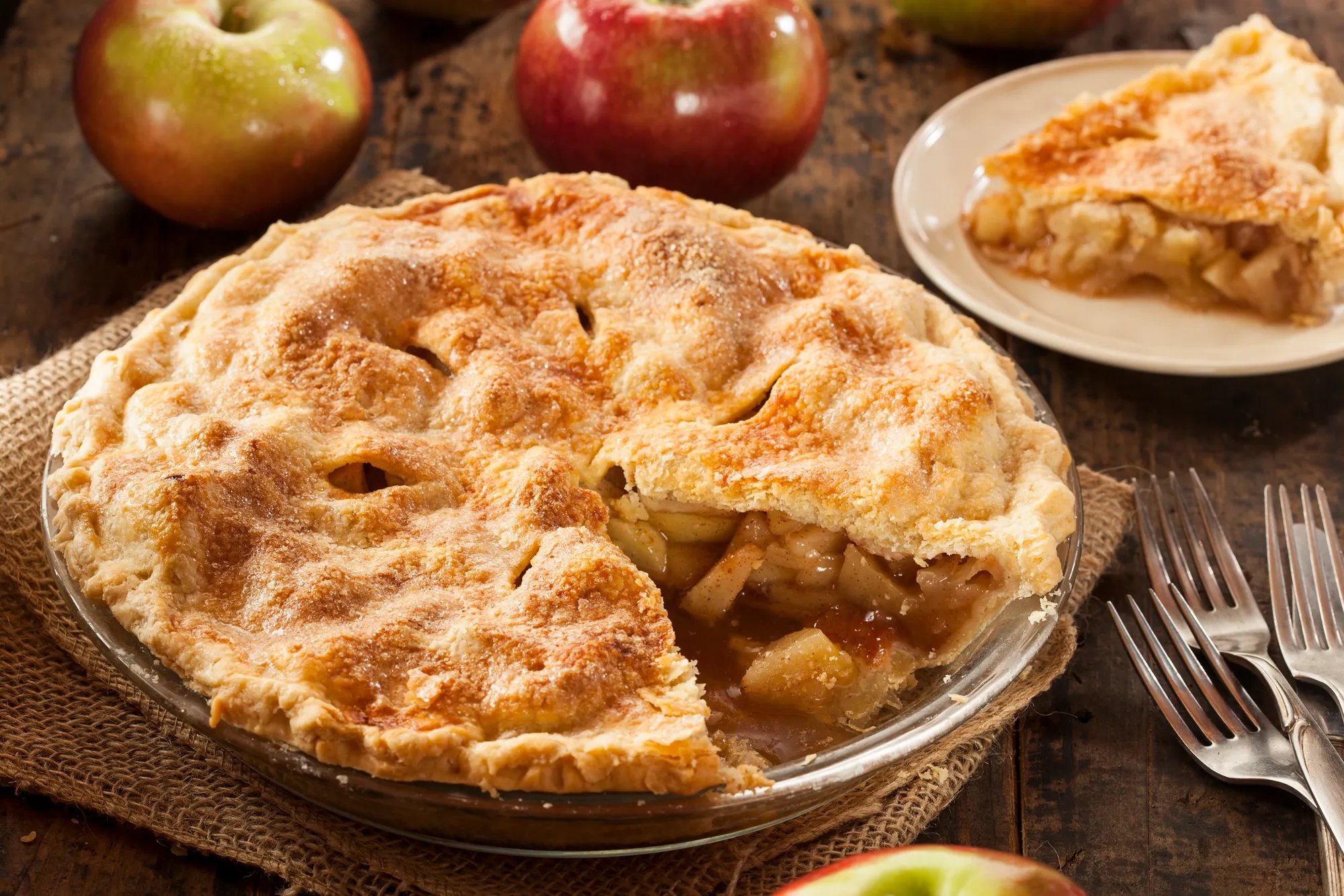 An apple pie with a slice cut out and showing on a plate