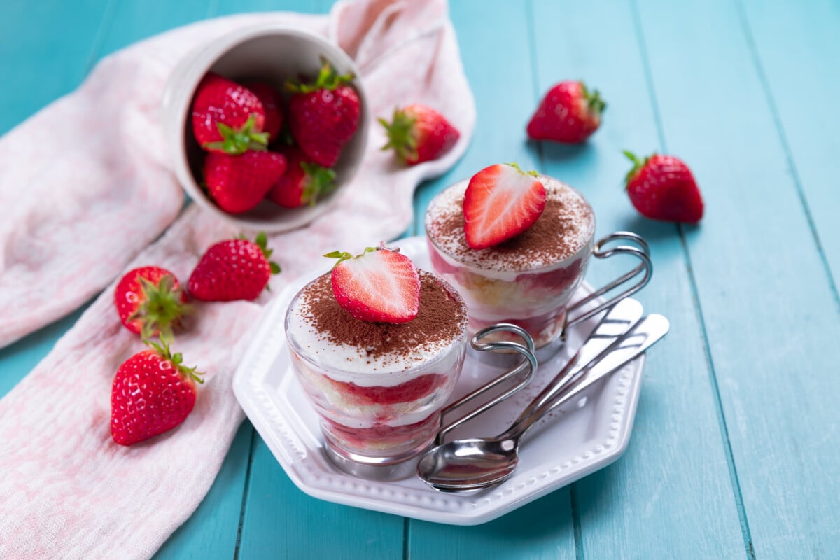 Strawberry tiramisu - traditional Italian dessert in a glass on a light blue background