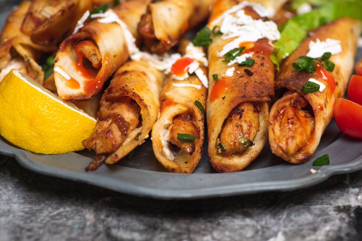Homemade chicken small tacos with dipping sauces and food ingredients on a plate