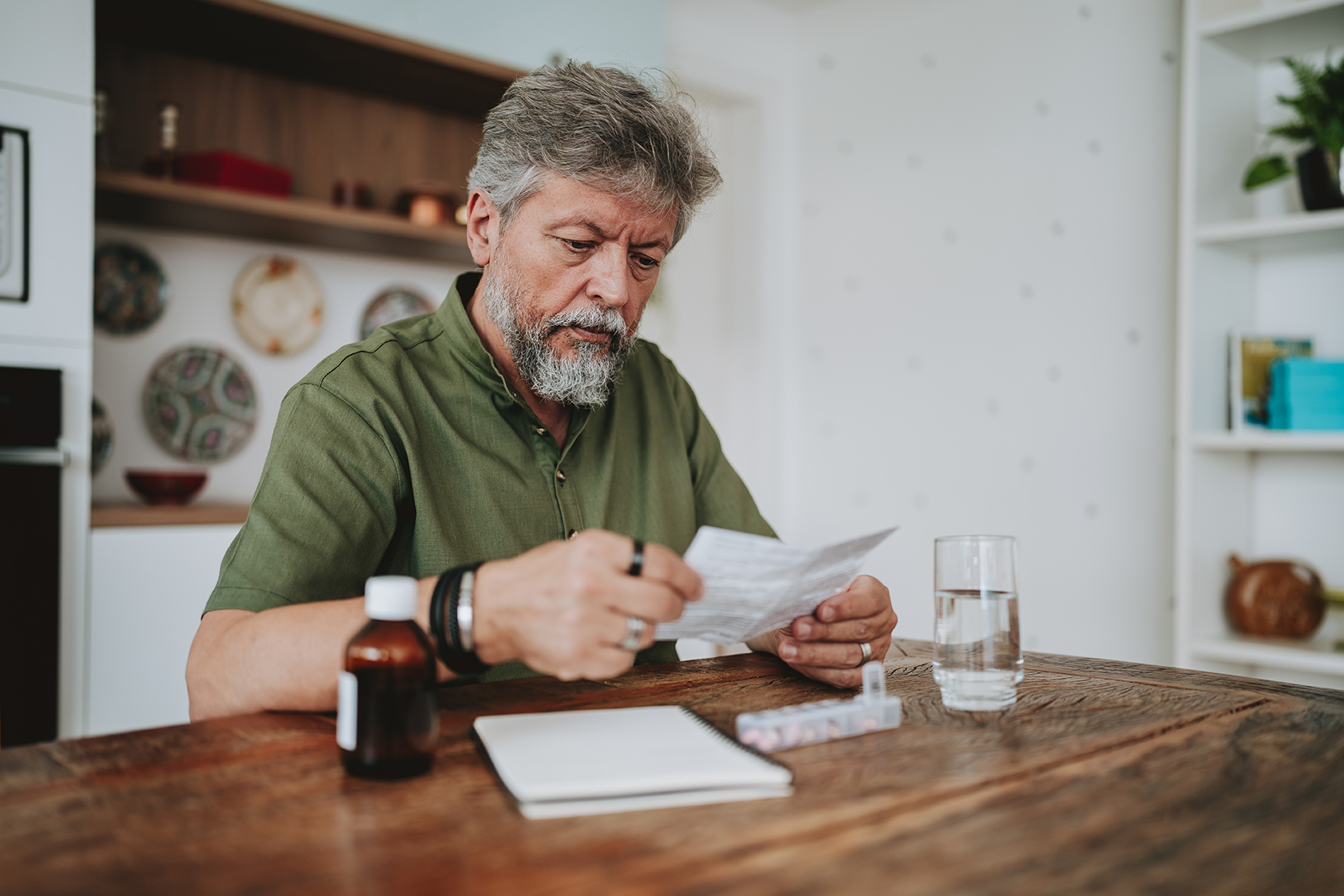 Adult male sits at table and reviews his medications