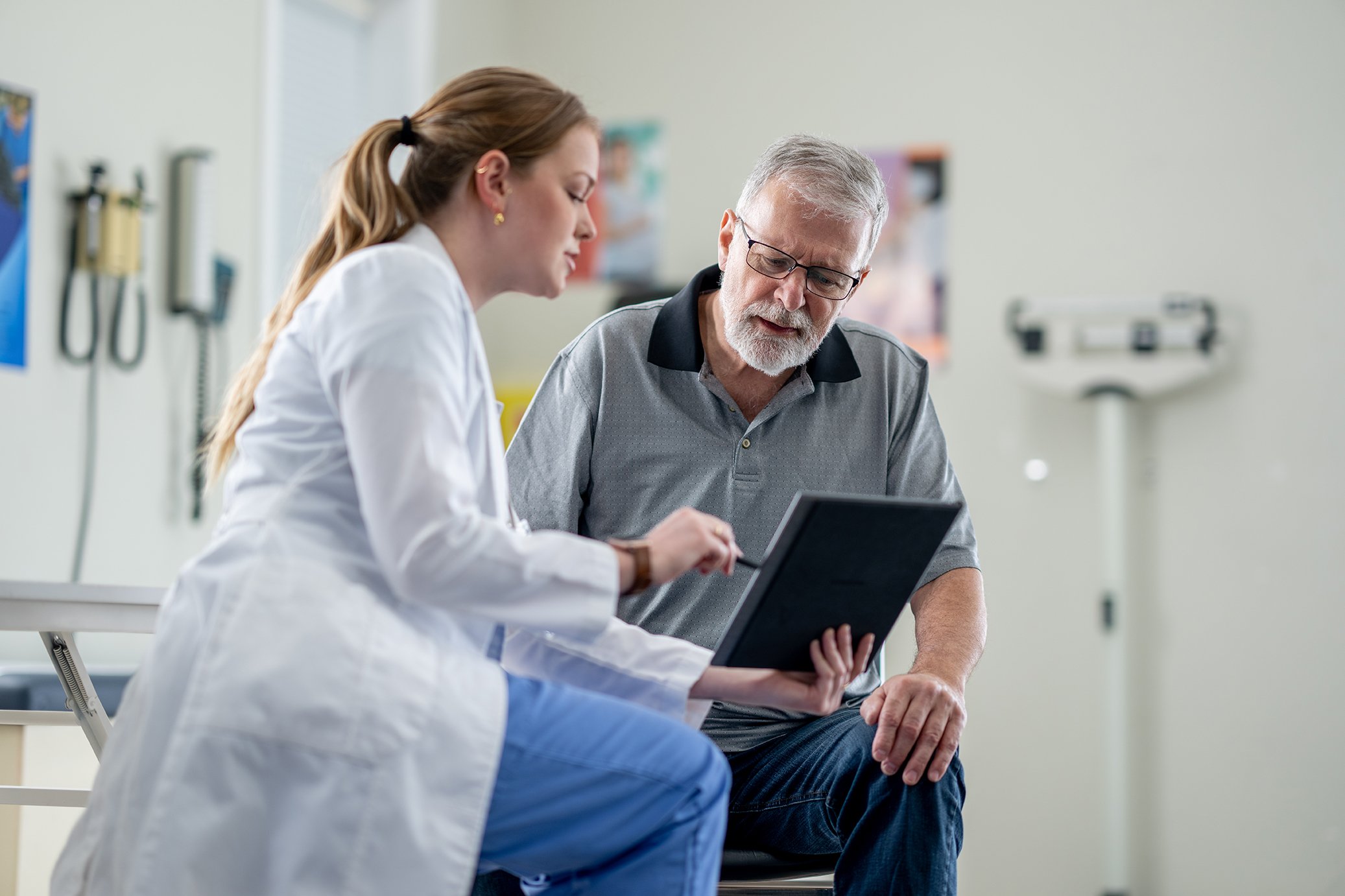 A female doctor shares test results on a tablet with a senior gentleman